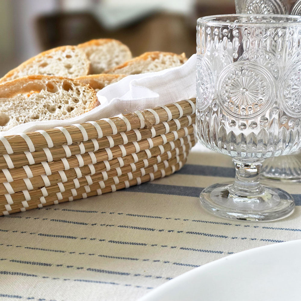 Bread in a basket with decorative glassware on a tablecloth