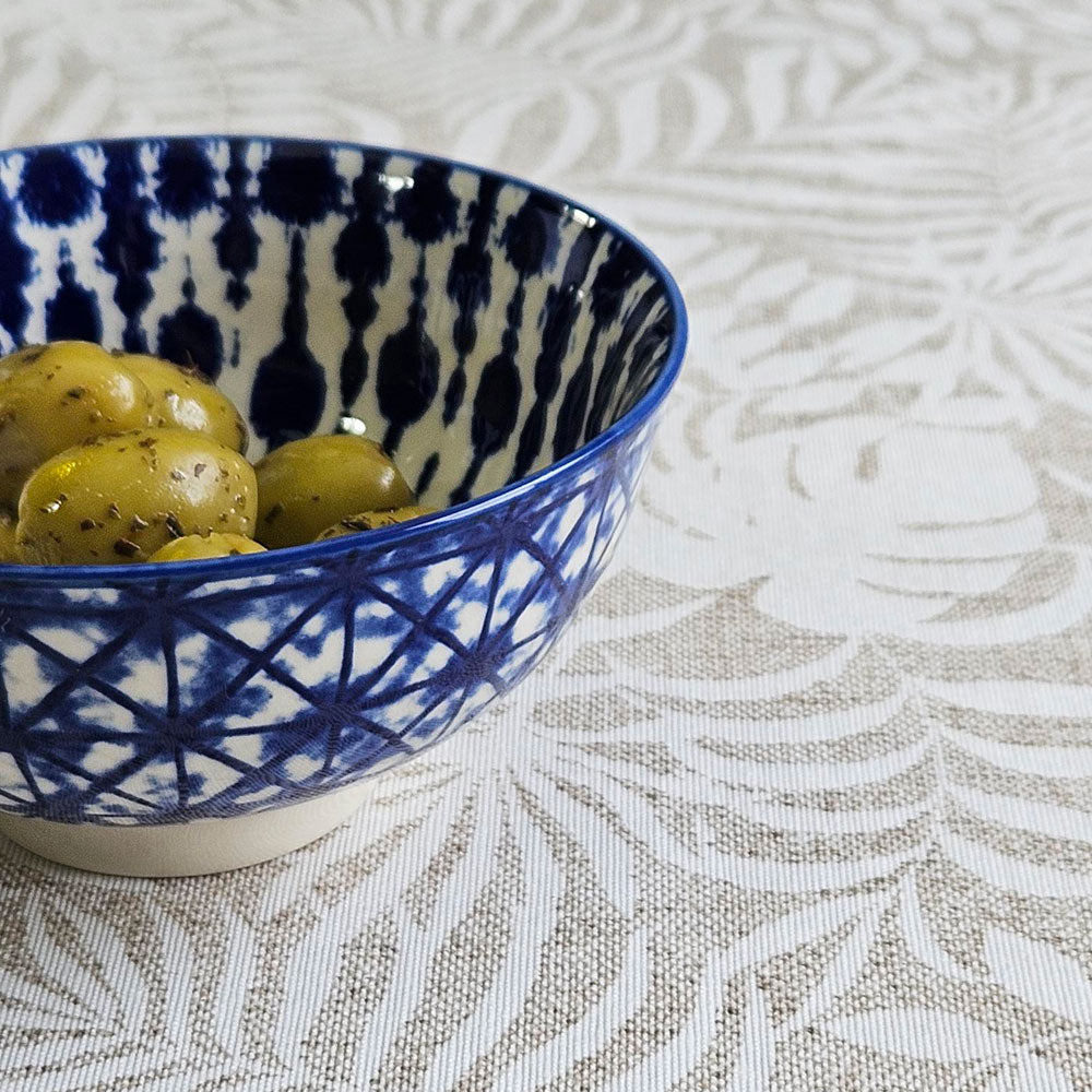 Ikat ceramic bowl filled with olives on top of Monstera oilcloth tablecloth