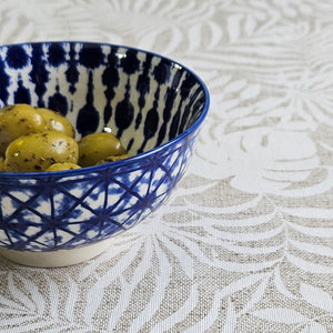 Ikat ceramic bowl filled with olives on top of Monstera oilcloth tablecloth