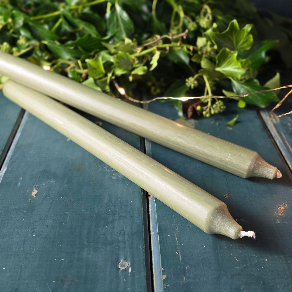 Moss green Danish dinner candles on a table with foliage and lights.