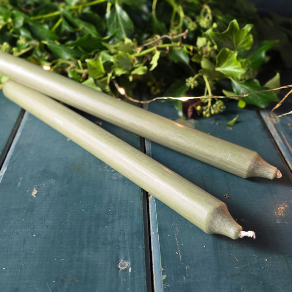 Moss green Danish dinner candles on a table with foliage and lights.