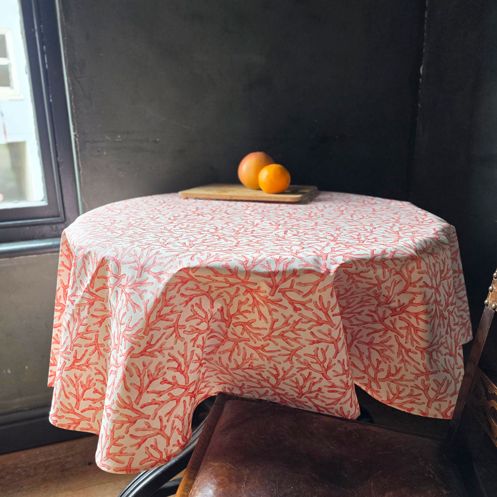 A circular orange coral wipe clean tablecloth with oranges on a table