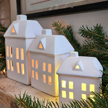 Christmas candle houses lit on a festive shelf