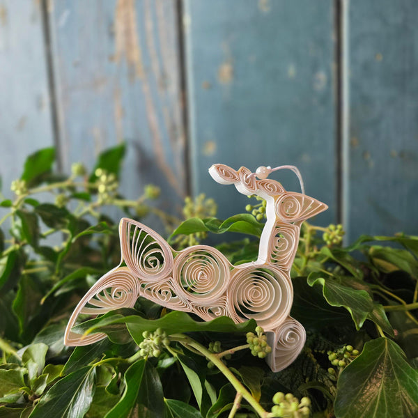 Leaping paper reindeer Christmas tree decoration against Christmas foliage.