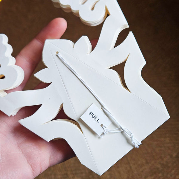 paper snowflake folded flat with hanging cord.