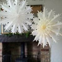 White paper snowflakes hanging in a room with a blurred background