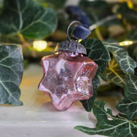 Antique style glass star tree decoration next t ivy foliage with twinkling blurred fairy lights.