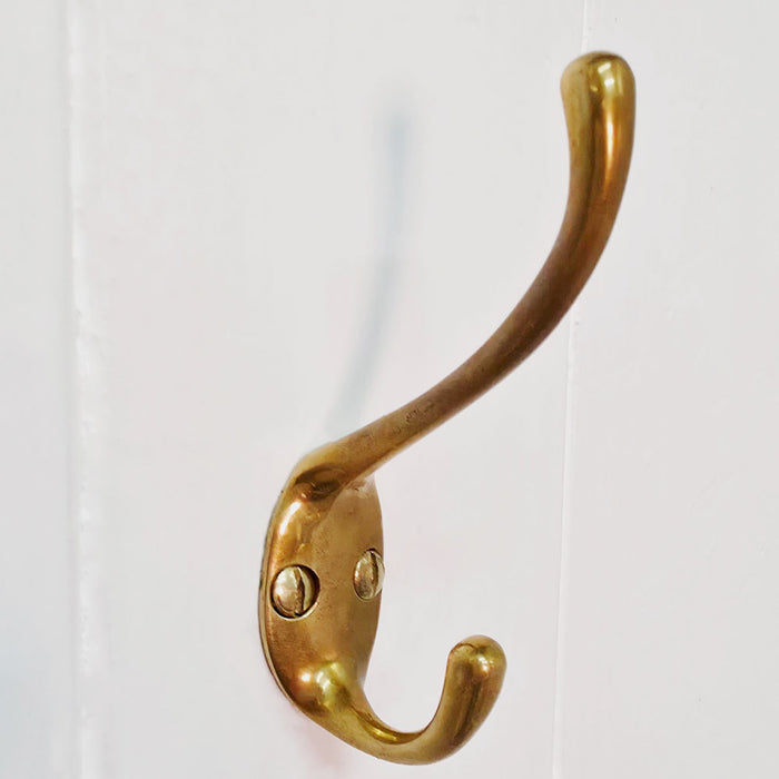 Brass wall hook on a white wooden door