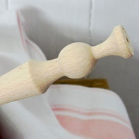 Close-up of a wooden porridge spurtle on a white background