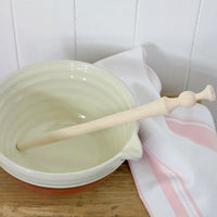 White bowl with wooden porridge spurtle on a white tiled wall background