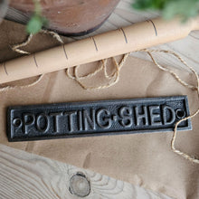 Cast iron potting shed plaque on a table with paper and twine