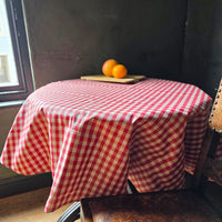 Red gingham round tablecloth on a circular table.