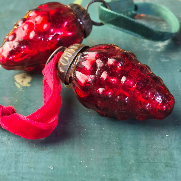 Vintage red glass Christmas baubles on a blue surface.