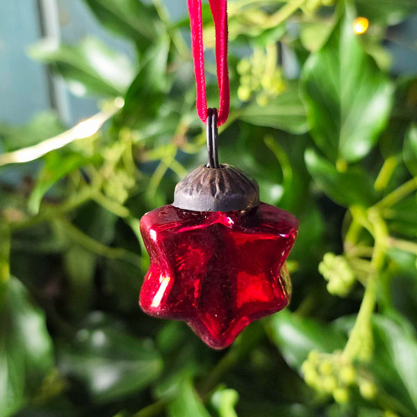 Red glass star Christmas decoration on a red velvet hanger.