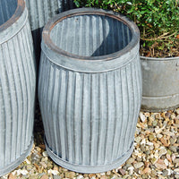 Round galvanised garden planter on a gravel yard.