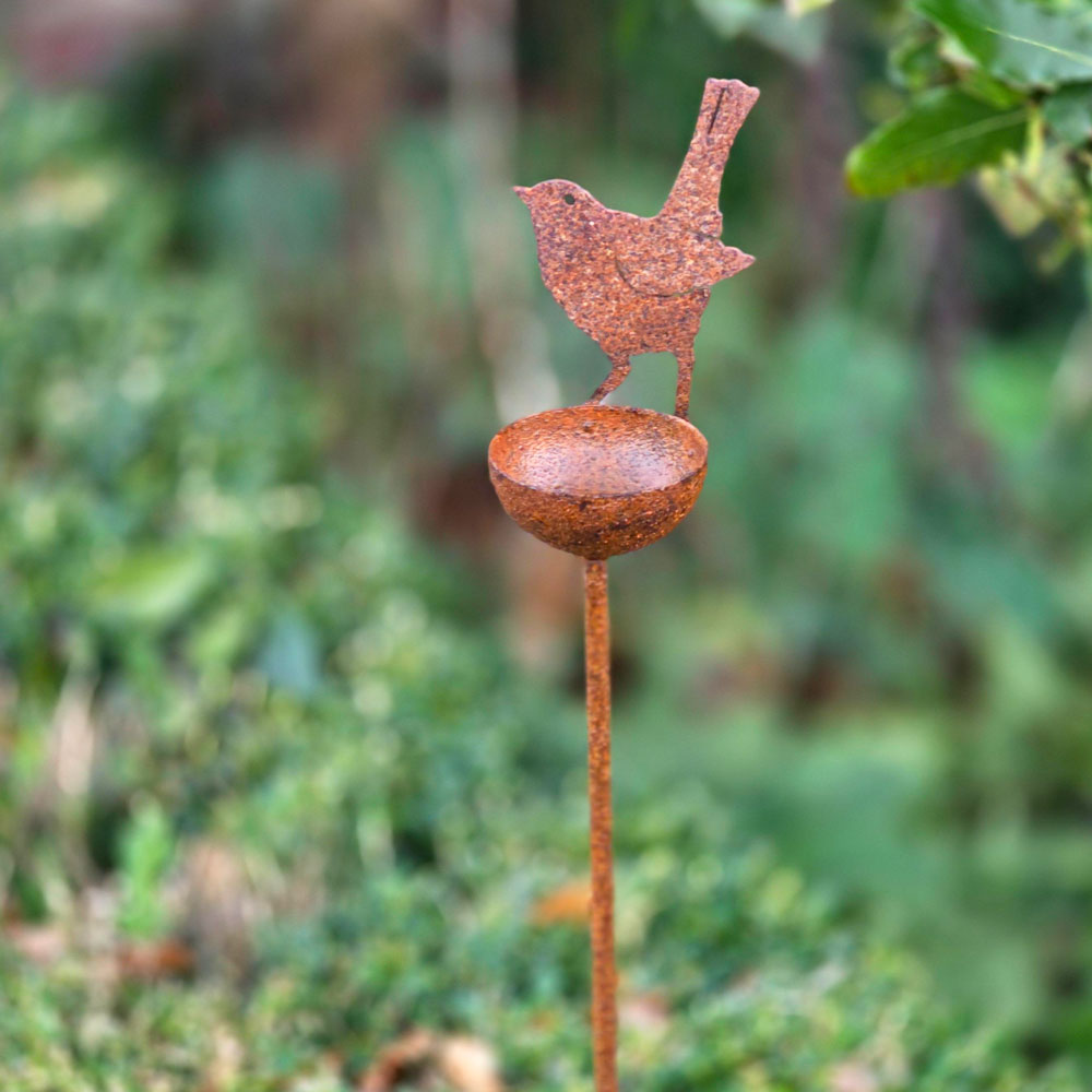 Metal bird feeder garden stake with bird design on a blurred green background