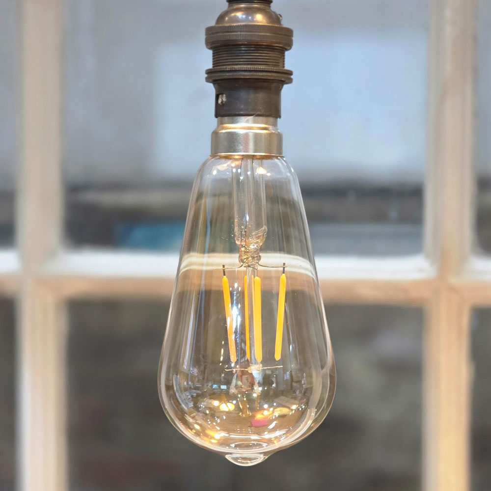Clear LED light bulb with visible filaments against a blurred background