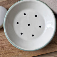 Aerial view of a round green and white enamel soap dish