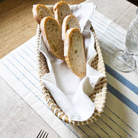 Basket of bread slices on a striped tablecloth with a glass and fork.