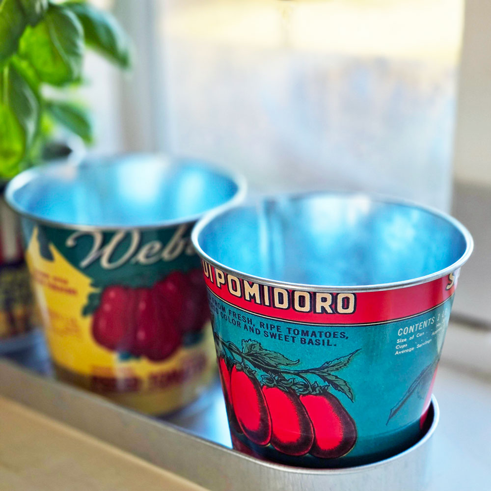 Two metal pots with tomato design labels on a surface.