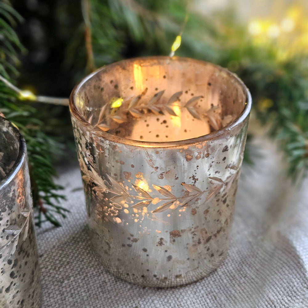 Antique silver glass lit tea light holder next to Christmas greenery