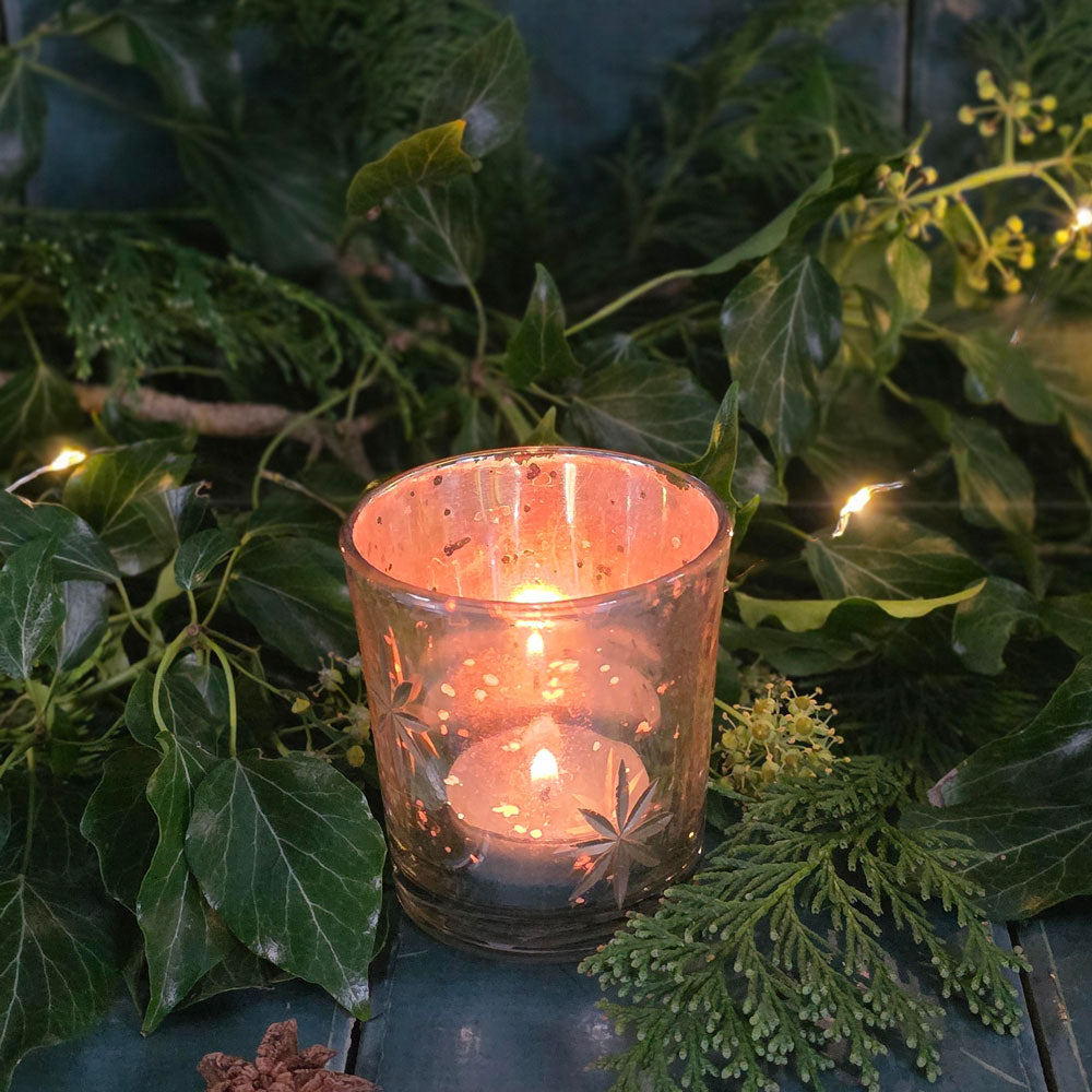 Antique glass tea light votive with lit tea light.