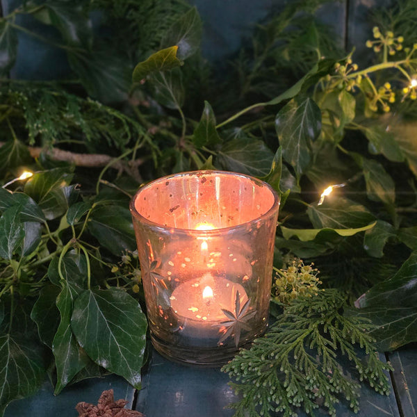 Antique glass tea light votive with lit tea light.