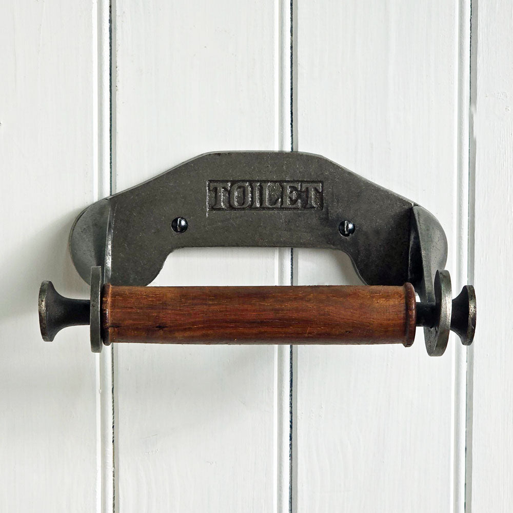 Vintage-style metal and wooden toilet paper holder on a white wooden panel background