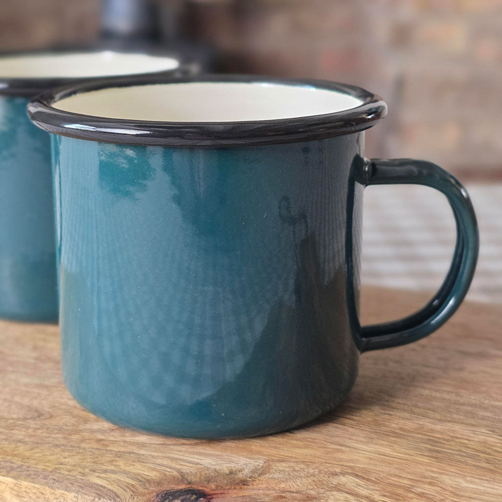 Single dark green enamelware retro style mug on a wooden board.