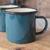 Single dark green enamelware retro style mug on a wooden board.
