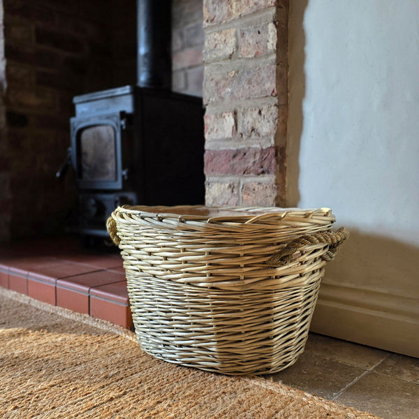 Small oval log and kindling basket next to log burning stove.