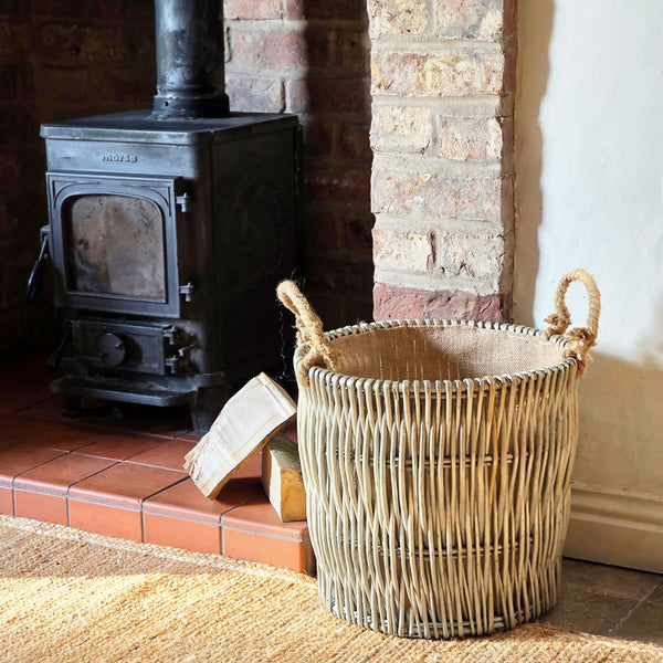 Wicker basket with handles in front of a brick fireplace