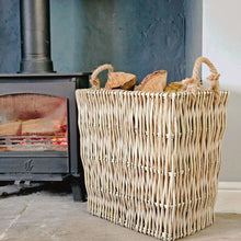 slim rectangular wicker log basket next to a lit log burner.