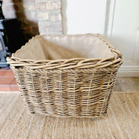 Square log basket on wheels next to a log burner.