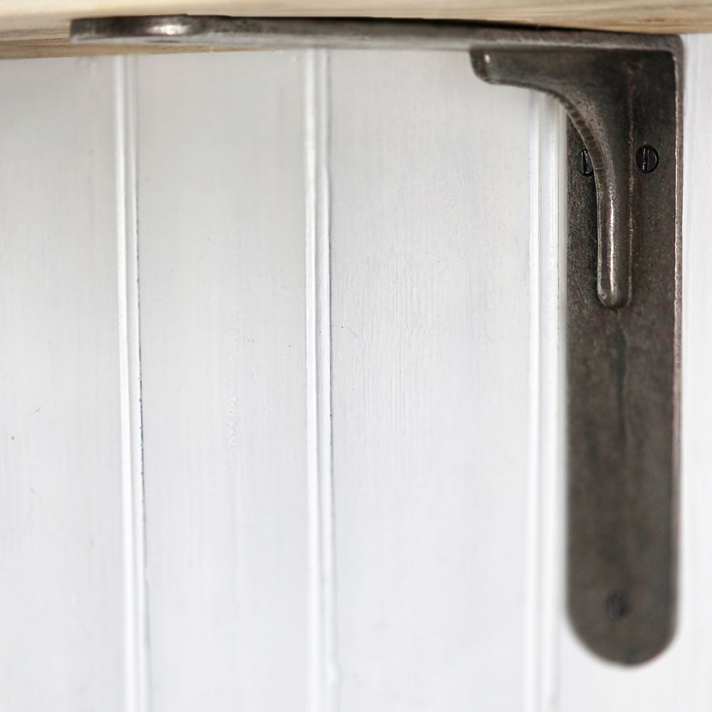 Close-up of a dark metal shelf bracket attached to a white paneled surface, with part of a light wood shelf edge visible at the top.