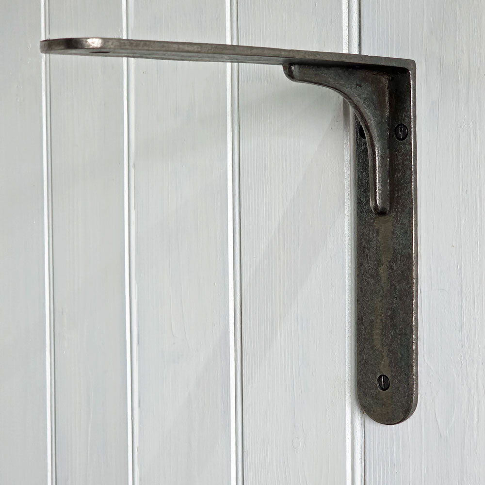 Cast iron Stocksbridge shelf bracket against white panelled wall.