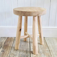 Wooden stool on a wooden floor with a white paneled wall background