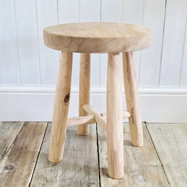Wooden stool on a wooden floor with a white paneled wall background