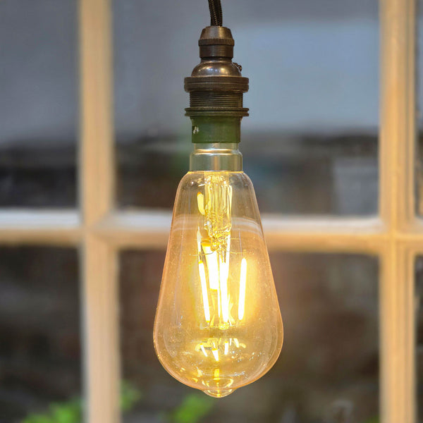 Vintage-style light bulb with a warm glow against a blurred window background