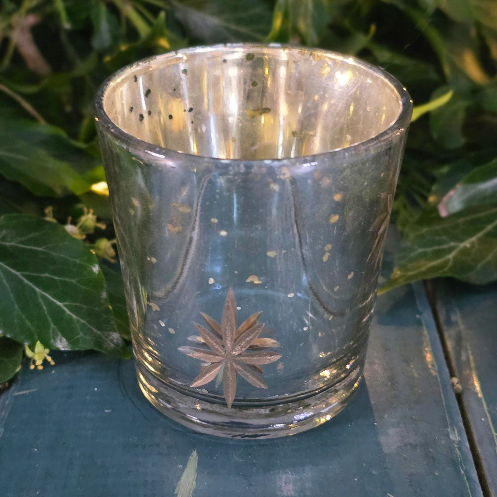 Clear glass candle holder with star design on a green surface