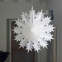 White paper snowflake hanging against a neutral background