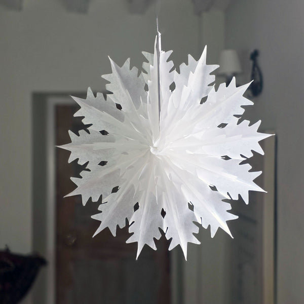 White paper snowflake hanging against a neutral background