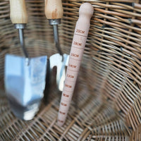 Gardening tools including a trowel and measuring tool on a wicker surface