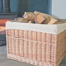 Large lined Bruton log basket filled with logs next a lit wood burning stove.