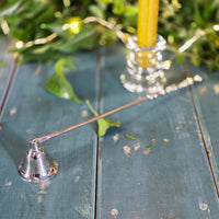 Silver coloured metal candle snuffer on a blue surface