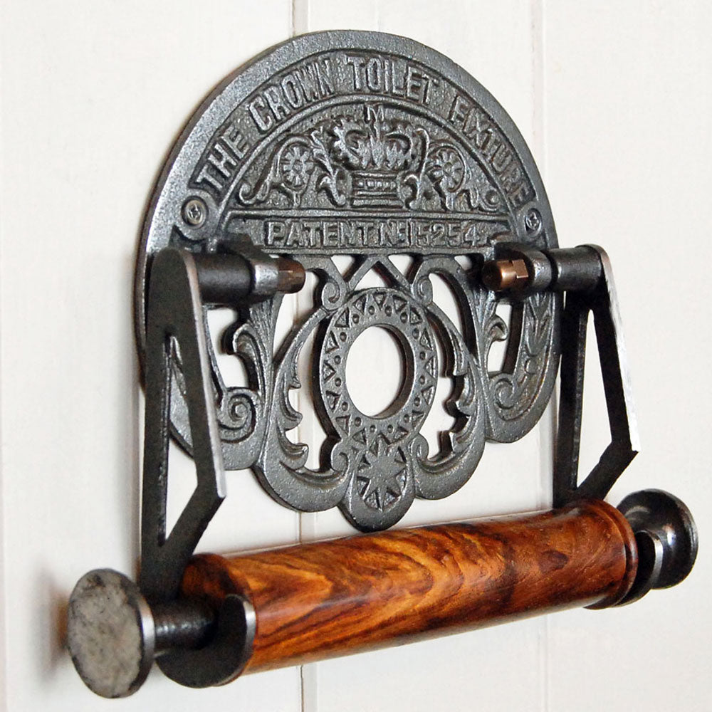Crown cast iron toilet roll holder with wooden spindle mounted upon a painted wooden panelled wall.