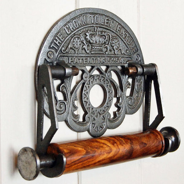 Crown cast iron toilet roll holder with wooden spindle mounted upon a painted wooden panelled wall.
