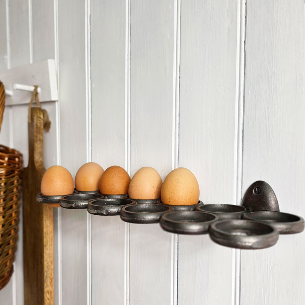 Eggs in a metal holder against a white paneled wall