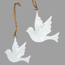 Enamel dove Christmas tree decorations against a grey background