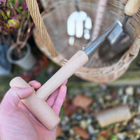Hand holding a gardening tool with a blurred garden background
